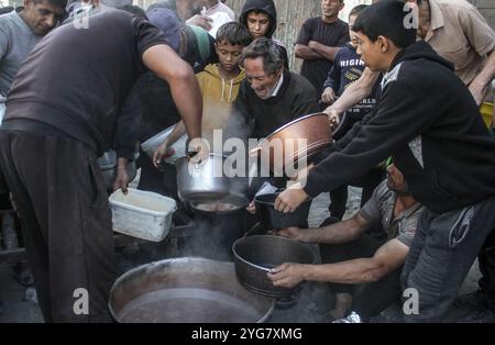 Gaza City, Palestine. 06 novembre 2024. Des Palestiniens déplacés de Beit Lahia et Jabalia reçoivent de la nourriture distribuée par des organisations caritatives dans le quartier de Nasser, dans la ville de Gaza, à Gaza. La crise alimentaire à Gaza se poursuit en raison du blocus israélien qui a été durci ces derniers jours. Crédit : SOPA images Limited/Alamy Live News Banque D'Images