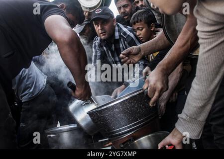 Gaza City, Palestine. 06 novembre 2024. Des Palestiniens déplacés de Beit Lahia et Jabalia reçoivent de la nourriture distribuée par des organisations caritatives dans le quartier de Nasser, dans la ville de Gaza, à Gaza. La crise alimentaire à Gaza se poursuit en raison du blocus israélien qui a été durci ces derniers jours. Crédit : SOPA images Limited/Alamy Live News Banque D'Images