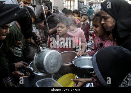 Gaza City, Palestine. 06 novembre 2024. Des Palestiniens déplacés de Beit Lahia et Jabalia reçoivent de la nourriture distribuée par des organisations caritatives dans le quartier de Nasser, dans la ville de Gaza, à Gaza. La crise alimentaire à Gaza se poursuit en raison du blocus israélien qui a été durci ces derniers jours. Crédit : SOPA images Limited/Alamy Live News Banque D'Images