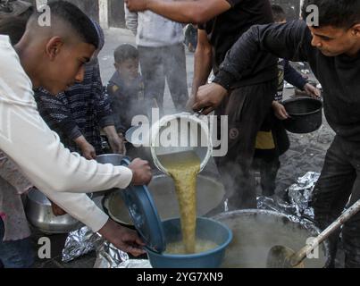 Gaza City, Palestine. 06 novembre 2024. Des Palestiniens déplacés de Beit Lahia et Jabalia reçoivent de la nourriture distribuée par des organisations caritatives dans le quartier de Nasser, dans la ville de Gaza, à Gaza. La crise alimentaire à Gaza se poursuit en raison du blocus israélien qui a été durci ces derniers jours. Crédit : SOPA images Limited/Alamy Live News Banque D'Images