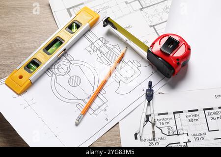 Différents dessins techniques, niveau de bâtiment, ruban à mesurer, crayon et séparateurs sur table en bois, vue au-dessus Banque D'Images