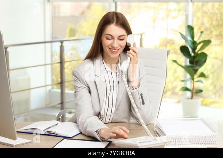 Banquier parlant au téléphone à table dans le bureau Banque D'Images