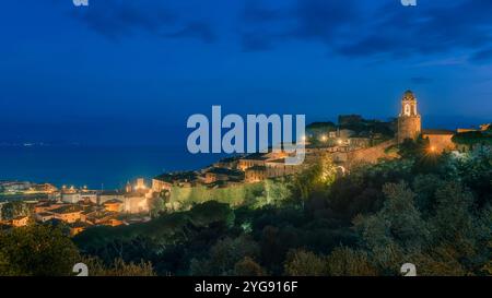 Heure bleue sur Castiglione della Pescaia, la vieille ville illuminée, la mer et l'île de Giglio en arrière-plan. Maremme, région Toscane, Italie, Europe Banque D'Images