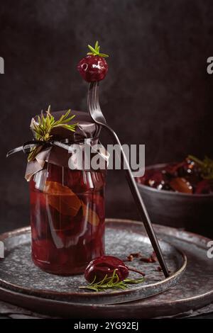 Prunes marinées aux épices dans un pot en verre sur la table de cuisine Banque D'Images