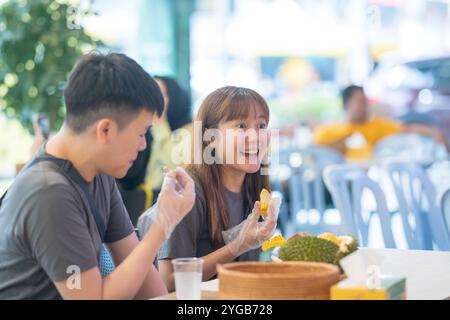 Juin 2024. Un couple chinois-malaisien dans leur conversation des années 30 tout en mangeant du durian dans un célèbre restaurant populaire auprès des touristes à Kuala Lumpur, en Malaisie. Banque D'Images
