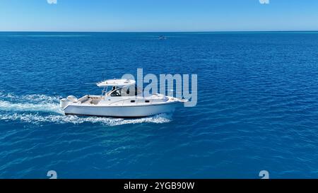 Un drone dynamique capturant un bateau de course qui traverse les superbes eaux des Bermudes, créant des éclaboussures et des sentiers dans la mer Banque D'Images