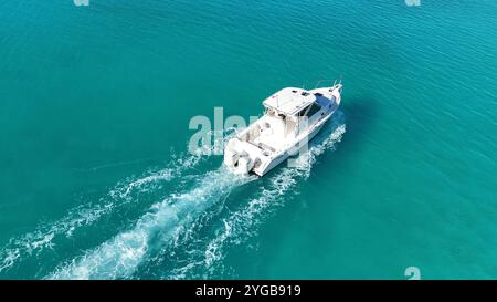 Un drone dynamique capturant un bateau de course qui traverse les superbes eaux des Bermudes, créant des éclaboussures et des sentiers dans la mer Banque D'Images