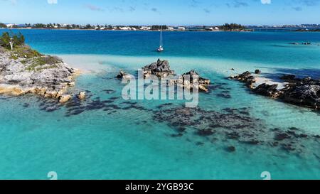 Un drone dynamique capturant un voilier se déplaçant sur les eaux magnifiques des Bermudes, créant des éclaboussures et des sentiers dans la mer turquoise cristalline Banque D'Images