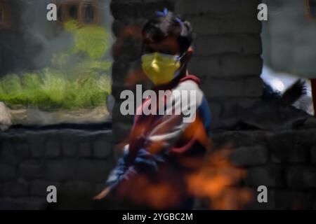 Un parent attend près du bûcher en feu de la victime du COVID-19 sur un terrain de crémation à Srinagar, au Cachemire administré par l’Inde, le 27 mai 2021. L’Inde a signalé 211553 nouveaux cas de covid-19 et 3842 décès au cours des dernières 24 heures. Banque D'Images