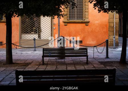 Bologne, Italie. 9 octobre 2024 - place (Piazza Galileo Galilei) avec des bancs devant un bâtiment orange Banque D'Images