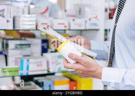 Manuel du pharmacien vérifiant l'inventaire de la pharmacie dans l'entrepôt de stockage. Le personnel de l'atelier de médecine vérifie la liste des noms d'expiration des médicaments. Banque D'Images