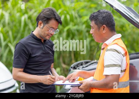 Man car Problem accident panne signant le document d'assurance du contrat de réclamation avec l'agent au bord de la route Banque D'Images