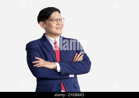 Bras confiant asiatique intelligent d'homme d'affaires plié isolé sur fond blanc. Homme heureux dans les croix de bras de costume d'affaires portant des lunettes. Banque D'Images
