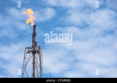 Plate-forme de tour de torchage de cheminée à torche élevée à foyer de gaz méthane dans une usine pétrolière de raffinerie ou brûlage de flamme sur un procédé d'extraction de pétrole offshore. Banque D'Images