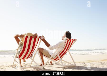 Bord de mer, couple et se détendre sur chaise pour la pause, le soutien et le lien avec amour à Maurice. Retour, les gens et la relation sur la chaise longue à la plage en vacances Banque D'Images