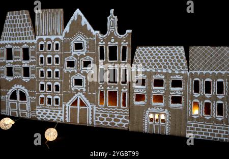 Panorama de vieilles maisons. Fabriqué à la main. Les maisons sont découpées dans du carton. Peint en blanc. Fond noir. Il y a de la lumière dans les fenêtres. Devant le Banque D'Images