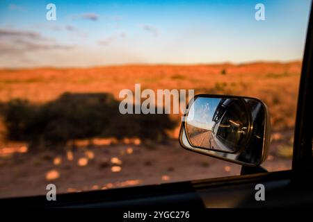 Road trip vue passager regardant par la fenêtre depuis un véhicule en mouvement à l'heure dorée dans l'outback. Avec rétroviseur latéral et réflexion du véhicule Banque D'Images