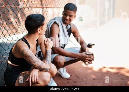 Basket-ball, fitness ou parler avec un homme et une femme sur le terrain ensemble pour le sport ou l'entraînement. Pause, conversation et eau avec l'équipe athlète de joueur Banque D'Images