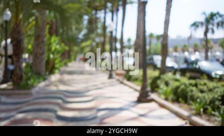 Vue dégagée de la promenade colorée bordée de palmiers à alicante, en espagne, au cours d'une journée ensoleillée avec des personnes et des véhicules flous en arrière-plan, crea Banque D'Images