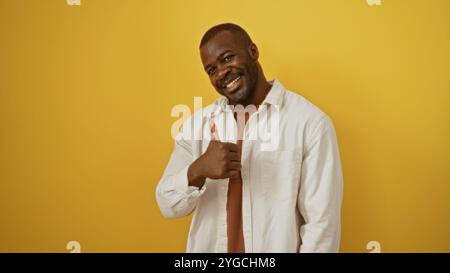 Beau jeune homme afro-américain souriant et donnant les pouces vers le haut sur fond jaune isolé Banque D'Images