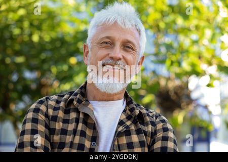 Portrait d'homme senior souriant dans la chemise à carreaux à l'extérieur Banque D'Images