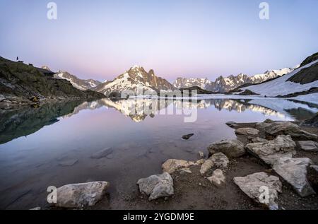 Ambiance du soir avec ciel rose du soir, paysage de montagne avec cabane de montagne refuge du Lac Blanc au coucher du soleil, reflet de l'eau au Lac Blanc, sommets montagneux Banque D'Images