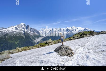 Alpiniste sur un sentier de randonnée devant un paysage montagneux, vue sur les sommets de l'aiguille verte, les grandes Jorasses et le Mont Blanc du Mont Bla Banque D'Images