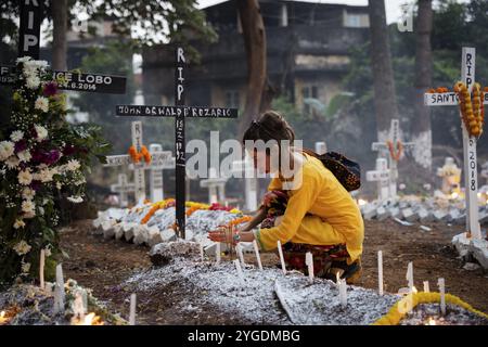 Les gens de la communauté chrétienne allument des bougies et offrent des prières sur la tombe de leur parent pendant l'observation de la journée de toutes les âmes, à Guwahati, Indi Banque D'Images