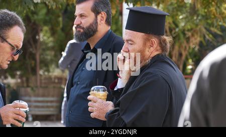 Hommes, y compris un prêtre orthodoxe, buvant et bavardant à l'extérieur, visite du président allemand Frank-Walter Steinmeier à Kandanos le 31 octobre 2024, G. Banque D'Images