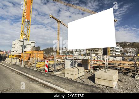 Panneau d'affichage vierge sur un chantier de construction avec grues Banque D'Images