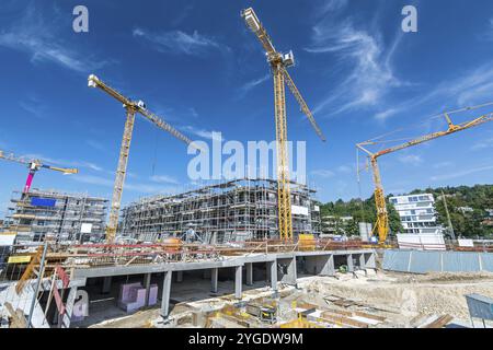Grand chantier de construction avec fondations, grues, échafaudages et bâtiments partiellement finis Banque D'Images