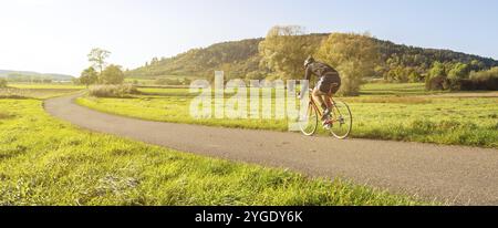 Vue panoramique d'un cycliste sur un vélo de course dans un paysage pittoresque paysage rural d'automne pendant la belle lumière de l'après-midi Banque D'Images