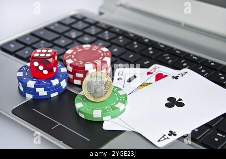 Jouer aux cartes, jetons de casino et pièce d'euro sur un clavier d'ordinateur portable symbolisant le jeu en ligne Banque D'Images