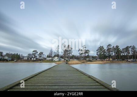 Lever de soleil sur un lac en automne. Une jetée en bois se jette dans l'eau, tandis que l'herbe s'est établie sur la plage de sable. Le lac et la plage au lac V Banque D'Images