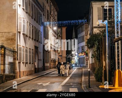 Strasbourg, France - 23 déc. 2024 : rue confortable de Strasbourg illuminée par des lumières festives et surveillée par une caméra de surveillance, capturant une scène nocturne paisible Banque D'Images