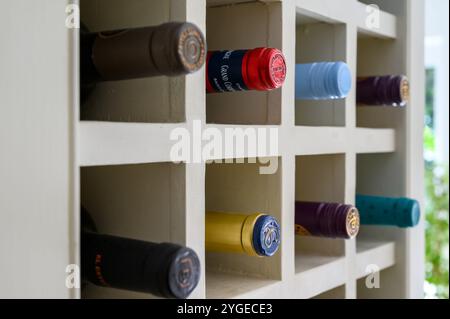 Gros plan vue latérale d'une unité d'étagère de support de vin en bois avec une variété de dessus de bouteilles dépassant. Banque D'Images