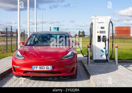 Voiture américaine entièrement électrique rouge Tesla Model 3 Dual Motor a une charge rapide dans le parking avec la station de charge super rapide Ignitis SUR Banque D'Images