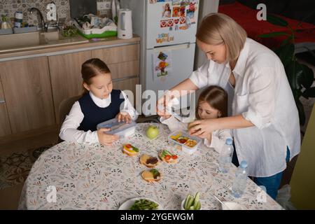 Routine matinale d'emballage de déjeuners scolaires sains dans la cuisine Banque D'Images