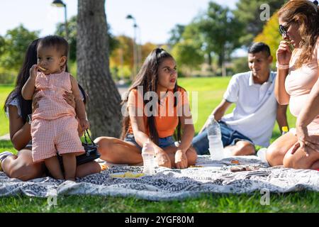 Famille latine mangeant dans un parc par une journée ensoleillée Banque D'Images