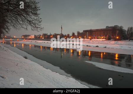 uzhhorod, ukraine - 06 Jan 2019 : scène nocturne de la rivière uzh. lanterne sur le remblai. lumière du centre-ville reflétant dans l'eau. neige sur le rivage Banque D'Images