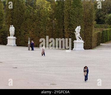 Vienne, Autriche - 6 octobre 2024 : jardins du palais de Schönbrunn avec des visiteurs se promenant parmi des sculptures, des haies bien entretenues et des avenues bordées d'arbres sur un Cl Banque D'Images