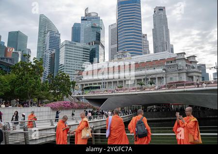 20.10.2024, Singapur, Republik Singapur, Asien - Eine Gruppe buddhistischer Moenche in ihren traditionellen orangenen Roben besucht den Merlion Park am Ufer des Singapore River in Marina Bay mit dem Fullerton Hotel und dem CBD Geschaeftszentrum im Hintergrund. *** 20 10 2024, Singapour, République de Singapour, Asie Un groupe de moines bouddhistes dans leur robe orange traditionnelle visite Merlion Park sur les rives de la rivière Singapour à Marina Bay avec l'Hôtel Fullerton et le centre d'affaires CBD en arrière-plan Banque D'Images