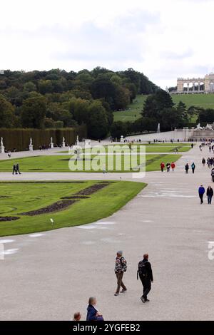 Vienne, Autriche - 6 octobre 2024 : jardins du palais de Schönbrunn avec des visiteurs se promenant parmi des sculptures, des haies bien entretenues et des avenues bordées d'arbres sur un Cl Banque D'Images