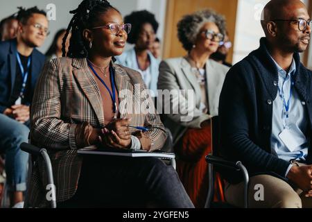 Groupe diversifié de professionnels lors d'une conférence d'affaires, axée sur une présentation. Collègues assis attentivement dans un auditoire. Banque D'Images