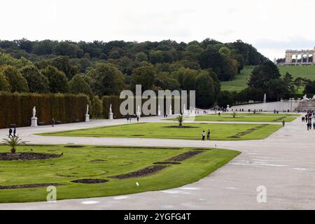 Vienne, Autriche - 6 octobre 2024 : jardins du palais de Schönbrunn avec des visiteurs se promenant parmi des sculptures, des haies bien entretenues et des avenues bordées d'arbres sur un Cl Banque D'Images