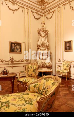 Vienne, Autriche - 6 octobre 2024 : salon jaune dans le palais de Schönbrunn – élégant mobilier rococo du XVIIIe siècle, poêle doré et tapisserie florale Ref Banque D'Images