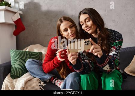 Deux amis apprécient l'esprit des fêtes, partageant le rire et la chaleur dans des chandails confortables tout en célébrant à la maison. Banque D'Images