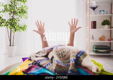 Joyeuse fille entourée de vêtements colorés lève les mains dans un triomphe joyeux Banque D'Images