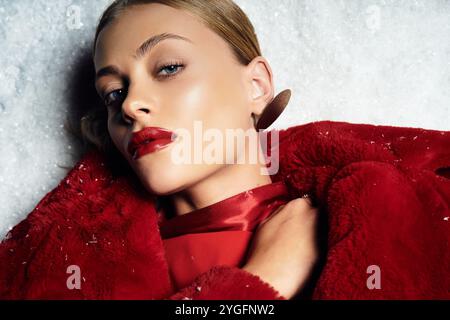 Une jeune femme étonnante aux lèvres rouges audacieuses met en valeur la mode hivernale dans un paysage enneigé. Banque D'Images