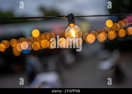 Gros plan sur des jeux de lumières lumineux chauds lors d'une réception de mariage en plein air à Malaga, en Espagne. L'effet bokeh ajoute une atmosphère rêveuse et romantique. Banque D'Images